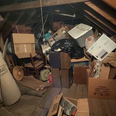 Attic filled with stored boxes and furniture before professional cleanout service