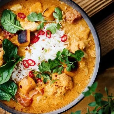 Coconut curry chicken in a bowl with spinach, herbs, and creamy sauce (THM S recipe).