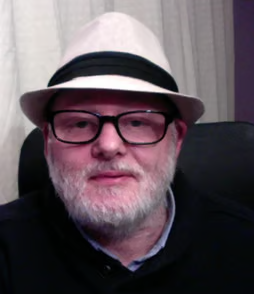 a man in a hat and glasses sitting in a chair