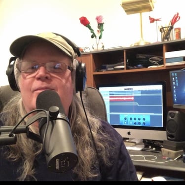 a man with long hair and glasses on a microphone