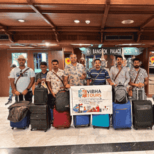 Group of travelers holding a Vibha Tours LLP banner, having successfully landed in Thailand