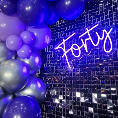 Purple Forty neon on a black shimmer wall with a matching purple garland at event in Logan.