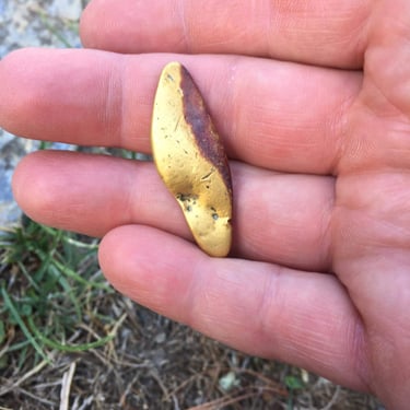 A large gold nugget being held in a hand, close up shot