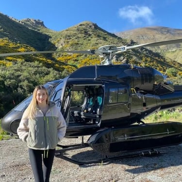 A photograph of a young woman, standing in front of a helicopter in Central Otago, New Zealand