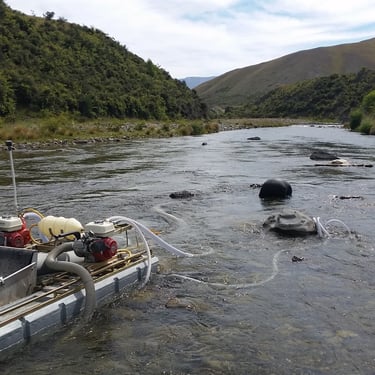 A photograph of a Keene Gold Dredge, in a river in New Zealand