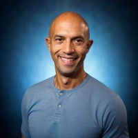 a man in a blue shirt smiling at the camera