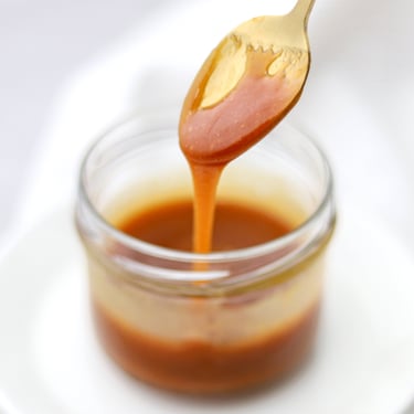 cuchara con dulce de leche en vaso de vidrio