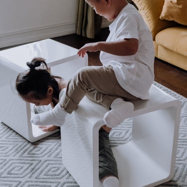 boy a girl playing with 2 white tables