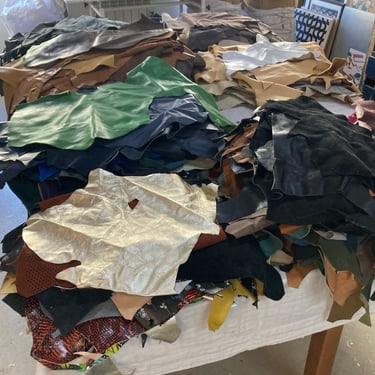 an assortment of leather pieces piled up over tables to be sorted