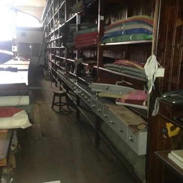 images of rollls of leather on shelves in disused warehouse
