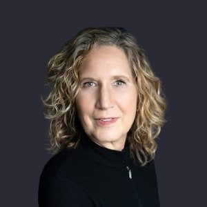 Deb Mrazek, a woman with curly blonde hair and a black top