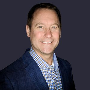 Mark Rose, a man in a suit and tie smiling