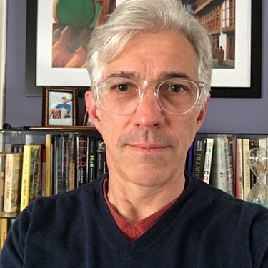 a man in a dark blue sweater and glasses