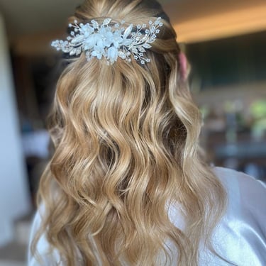 Half-up bridal hairstyle with soft waves and a delicate floral hairpiece for a romantic wedding look