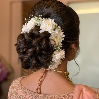 Elegant bridal bun decorated with white flowers for a wedding hairstyle