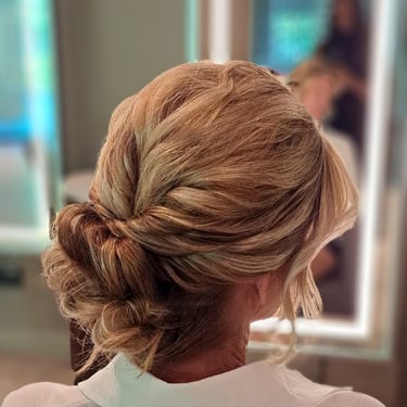 Bride with an elegant twisted low bun hairstyle, wearing a bridal robe with gold lettering