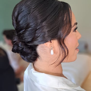 Elegant bridal updo with a sleek finish and soft face-framing curls for a classic wedding look