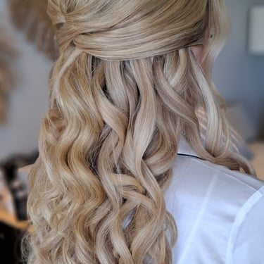 Half-up bridal hairstyle with loose curls and a delicate crystal headpiece for a soft wedding look