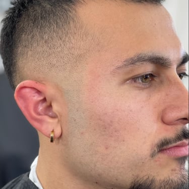 Side profile of a person with a fade haircut and a gold hoop earring.