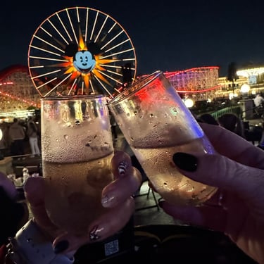 Couple toasting champagne in front of the Mickey Ferris Wheel at Disney California Adventure / night