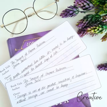Two printed bookmarks with written quotes on them. Glasses near by.