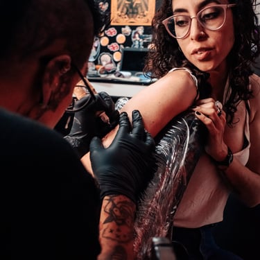 mujer tatuandose brazo lentes ace tatuajes