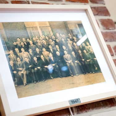 un cadre contenant une photo de classe d'étudiants de 1947 accroché au mur