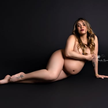 mujer embarazada posando sobre fondo oscuro