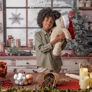 niño de pelo rizado abrazando osito con gorro de Papá Noel