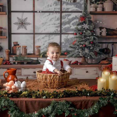 bebé con ún árbol de navidad al fondo una tarta al lado