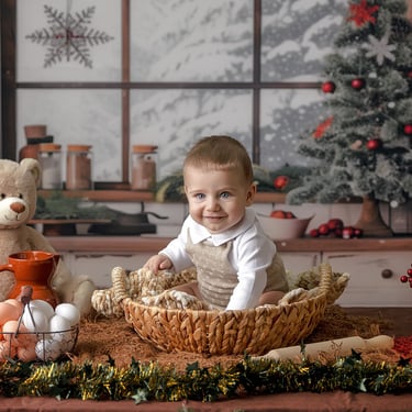 bebé sentado una cesta sobre una mesa con ún árbol de navidad al fondo