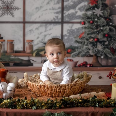 bebé sentado en una cesta con un árbol de navidad detrás
