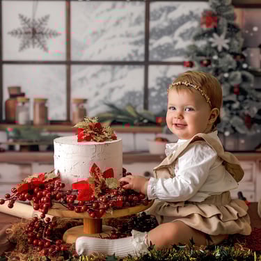 niña con tarta entre las piernas con ún árbol de navidad al fondo