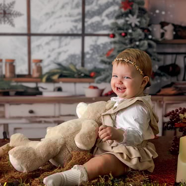 fotografía de navidad de una bebé sonriendo con un oso de peluche