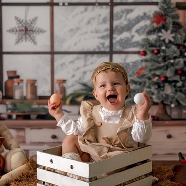 niña en una cajita con huevos en la mano con ún árbol de navidad al fondo