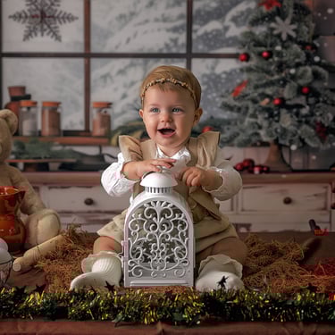 bebé sonriendo en un fondo de navidad con una lámpara entre las piernas