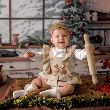 bebé en un fondo navideño sosteniendo un rodillo de amasar
