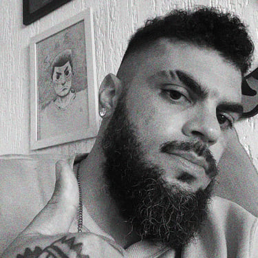 Um homem com barba, e uma tatuagem na mão fazendo joinha