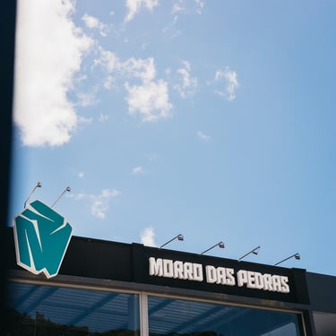 Fachada do CrossFit Morro das Pedras em Florianópolis com céu azul e destaque para o logo no sul da Ilha.