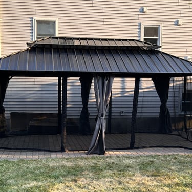 A 6-post gazebo assembled for a client in Peabody, MA. Black metal with gray privacy curtains and mosquito netting.