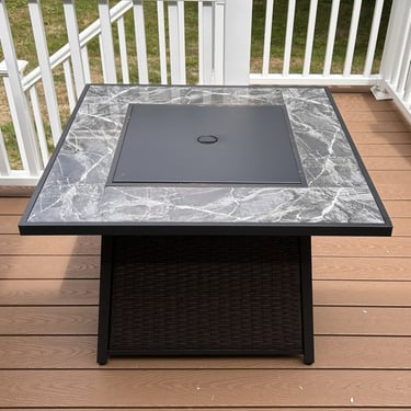 A DEKO Living firepit table with the lava rocks covered.