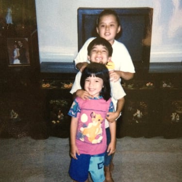 Photo of Stacey with her siblings as children, they have their heads stacked on one anothers.
