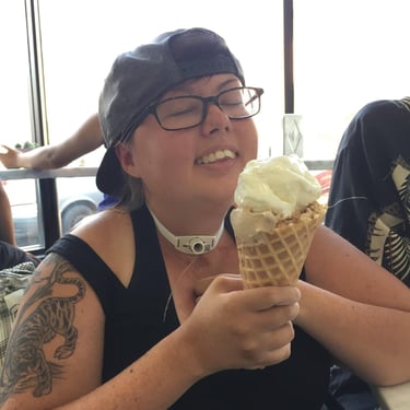 Photo of Stacey enjoying a ice cream cone. Her head is back with a big smile, her tattoo is visible