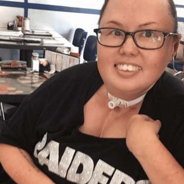 Photo of Stacey with hair pulled back and smiling with a Raiders tee shirt.