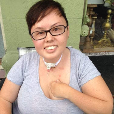 Photo of Stacey smiling on the sidewalk in front of green building.
