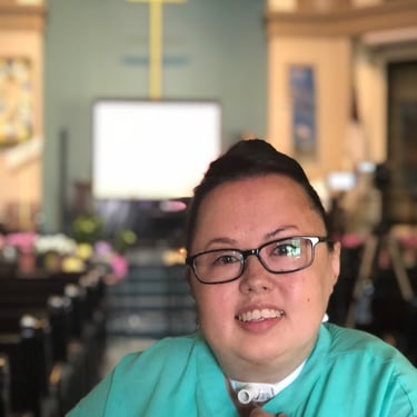 Photo of Stacey at church with cross in background.