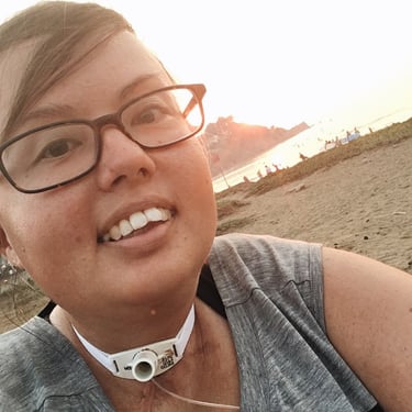 Selfie photo of Stacey at the beach. The sun is setting over the water.