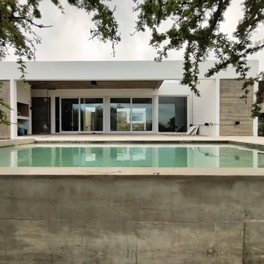 Una casa moderna de hormigón visto con galería vidriada y pileta de hormigon. diseñada por Arquitectura con sentido