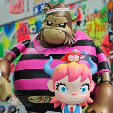 Close-up of designer art toys, featuring a large pink-and-black striped gorilla-like figure and a smaller cartoon girl with