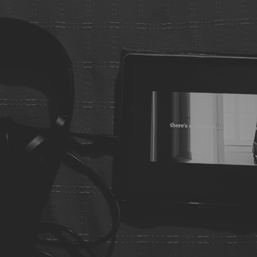 Audífonos y pantalla con cita de Bukowski, atmósfera **oscura** en B&N.